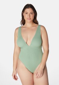 Ljusgrön ribbad baddräkt med djup urringning och breda axelband, med en högskuren design på benen.