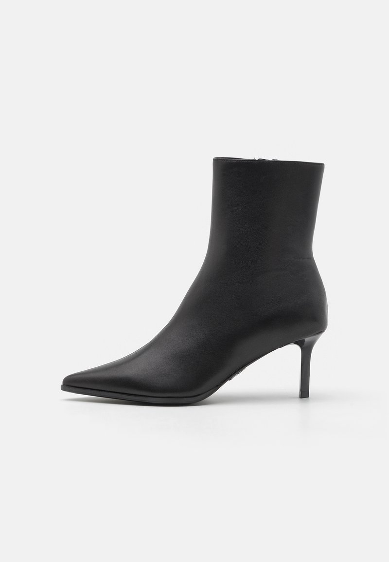 Zwarte leren enkelboot met een spitse neus en een slanke mid-height stilettohak, tegen een effen witte achtergrond.