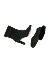 Botines negros con una textura brillante, puntera afilada y un tacón alto y delgado. Uno de los botines tiene un detalle de cremallera en el costado.