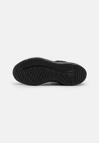 Semelle extérieure de sneaker noire avec une surface texturée, dotée d'une adhérence à motifs et de rainures de traction pour une stabilité et une durabilité accrues.