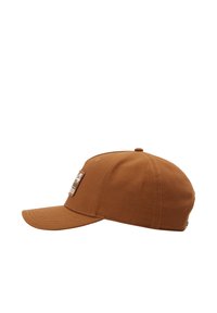 Gorra de algodón marrón con visera curva, que presenta un parche de marca rectangular en la parte delantera y una corona estructurada y redondeada.