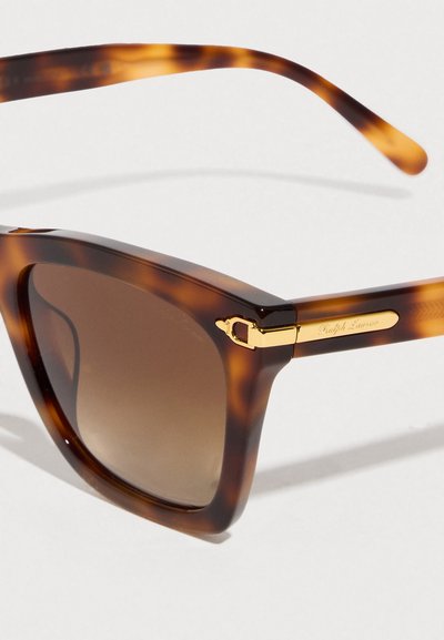 Γυαλιά ηλίου σε σχέδιο χελώνας με καφέ φακούς με διαβάθμιση, τετράγωνα πλαίσια και χρυσές λεπτομέρειες. Το λογότυπο είναι τυπωμένο στα πλαϊνά των βραχίονας.