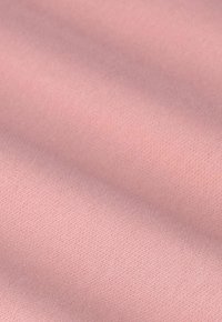 Tissu doux de couleur rose clair, avec un tissage fin et lisse, et de légers plis créant des ombres et une texture délicates.