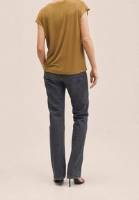 Un haut olive à manches courtes associé à un jean droit bleu foncé, offrant une coupe décontractée et une texture subtile. Sandales noires à talons hauts.