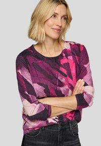 Lila und rosa Pullover mit abstraktem Muster, langen Ärmeln und rundem Ausschnitt. Der Stoff wirkt weich mit einer strukturierten Oberfläche und dezentem Glanz.