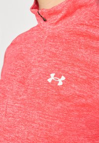 Röd, strukturerad atletisk kvartdragetopp med en liten vit Under Armour-logotyp på vänster bröst.