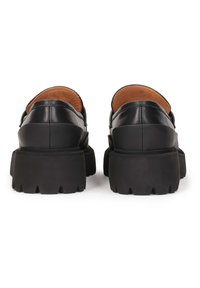 Chaussures en cuir noir avec une semelle épaisse et texturée noire et une finition lisse. Forme arrondie avec un léger talon et un design à dos ouvert.