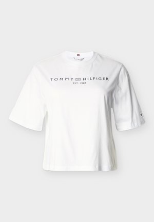 T-shirt en coton blanc à manches courtes, avec un col rond et un logo devant "TOMMY HILFIGER EST. 1985" en texte bleu marine.