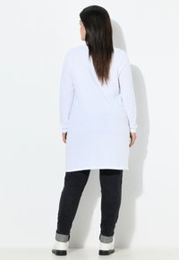 Witte tuniek met lange mouwen, gecombineerd met zwarte skinny jeans en enkellaarsjes, met een relaxte pasvorm en een gladde textuur.