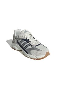 Jasnoszare sneakersy z granatowymi akcentami, siateczkowa i syntetyczna cholewka, trzy paski po boku oraz teksturowana gumowa podeszwa.