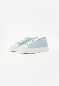 Sneaker in tela azzurro chiaro con punte in gomma bianca e suole bianche. Caratterizzate da stringhe bianche e cuciture sottili lungo i lati.