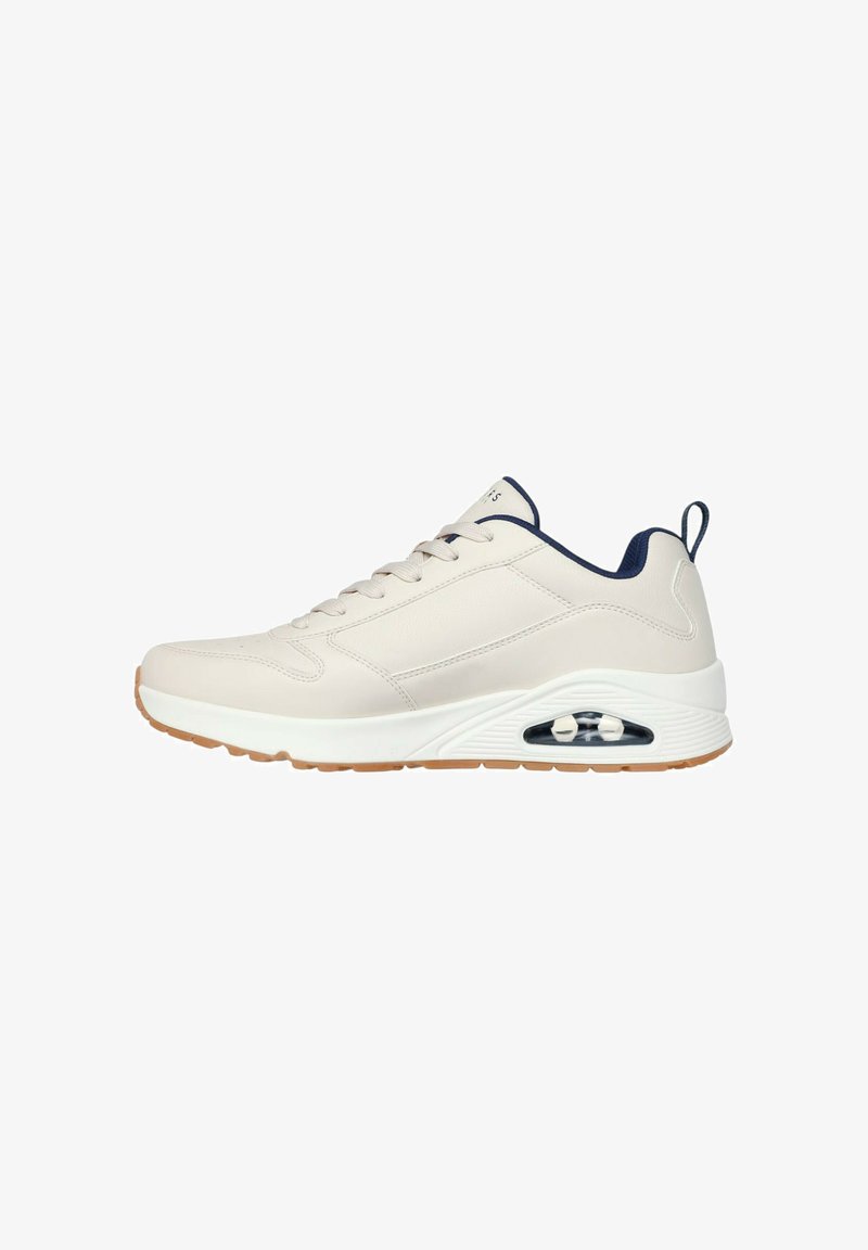 Sneaker atletica bianca e blu navy con suola a cuscinetto d'aria visibile, parte anteriore con lacci e suola in gomma color beige.