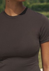 Sötétszürke testhezálló póló puha, rugalmas anyagból. Környakkal és rövid ujjakkal rendelkezik, sima felülettel.