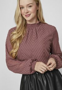 Ribbed mauve pusero, jossa on korkea kaula-aukko, viivoitettua kuviota, pitkät hihat joustavilla resoreilla ja rento istuvuus.