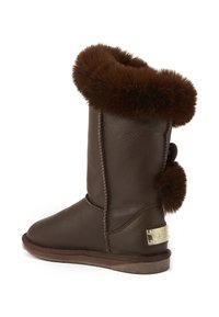 Botte en cuir marron avec un sommet en fourrure marron pelucheuse, texture lisse, bout rond et un petit détail en pompon à l'arrière.