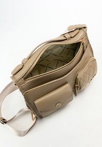 Borsa a mano beige in pelle con più scomparti, accessori in metallo dorato e una pochette circolare trapuntata. L'interno presenta una fodera a motivo.