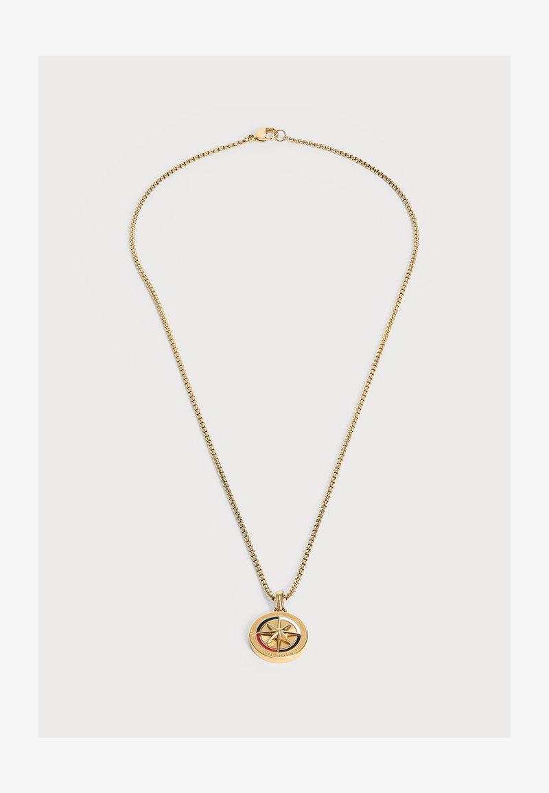 Collier délicat en chaîne d'or avec un pendentif rond présentant un motif d'étoile en relief au centre sur un fond blanc.