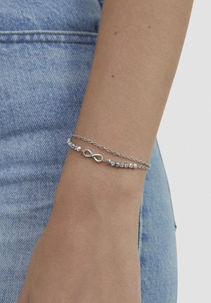 Silver chain bracelet featuring an infinity symbol and small beads. The design includes a mix of polished and textured surfaces.