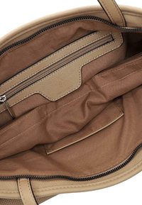 Interior de bolso de cuero beige con forro de tela marrón, un bolsillo con cremallera y un pequeño bolsillo abierto en el interior.