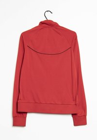 Chaqueta deportiva roja de manga larga con un cuello alto, textura suave y un diseño de yugo en la parte posterior. Presenta un detalle de ribete negro a lo largo del yugo.