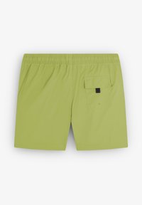 Shorts de bain verts avec une taille élastique, une poche arrière avec un rabat, et une texture de tissu lisse et léger.