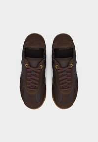 Paire de baskets décontractées à lacets en cuir marron foncé et daim, vues de dessus sur fond blanc.