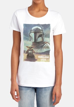 Weißes T-Shirt mit Mandalorianer-Helm und Grogu, die auf einer Wüstenlandschaft stehen, mit dem Text „Mandalorian und Grogu“ darunter.