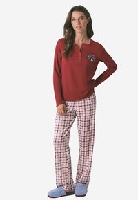 Red long-sleeve top with button detail, paired with white and red plaid pants featuring navy and burgundy accents. Blue slippers complete the outfit.