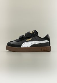 Μαύρο αθλητικό παπούτσι Puma με λευκή ρίγα, καφέ σόλα και δύο λουράκια βέλκρο για δέσιμο, φαίνεται από το πλάι σε ουδέτερο φόντο.