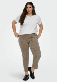 Bijela majica s natpisom "SUNDAY FUNDAY", uparena s bež hlačama s leopard uzorkom. Crne mokasine zaokružuju odjevnu kombinaciju. Glatka tekstura, ležeran kroj.