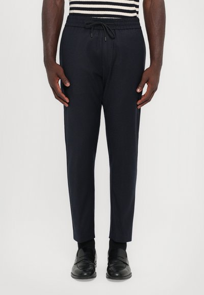 Navy Jogginghosen mit einem elastischen Bund und Kordelzug, mit einem tapered Fit. Das Material wirkt glatt mit einem dezenten Glanz.