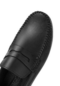 Schwarze Lederpantolette mit einer glatten, polierten Oberfläche, Stichdetails entlang der Kanten und einem dekorativen Riemen über der Oberseite.