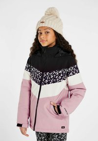 Giacca invernale viola, nera e bianca con motivo floreale e design a zigzag; presenta una chiusura con zip sul davanti e cappuccio. Abbinata a un berretto lavorato a maglia beige.