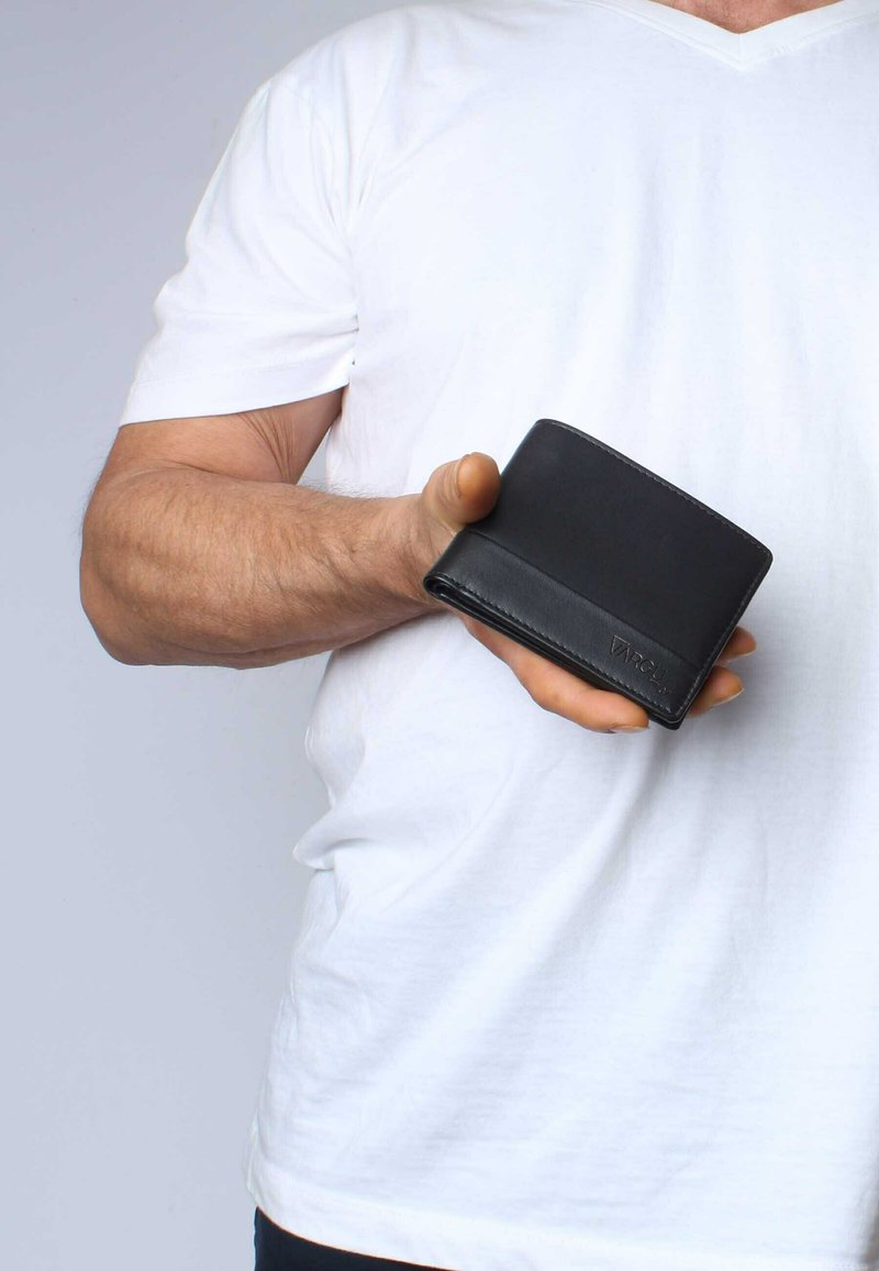 Black leather wallet held in a hand, featuring a smooth texture, a folded design, and minimalistic detailing with a logo embossed on the front.