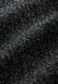 Texturiertes Schwarz- und Graufabric mit einer flauschigen Oberfläche, die unterschiedliche Dicken aufweist und eine weiche, griffige Haptik bietet. Keine ausgeprägten Muster oder Akzente.