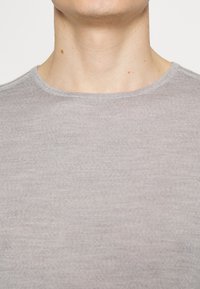 Grå, ribbad crewneck t-shirt i närbild, som visar upp den mjuka texturen och det släta tyget med en lätt lyster.