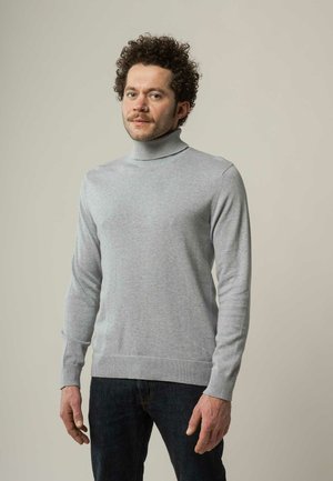 Grijze coltrui gemaakt van zachte stof, met lange mouwen en een geribbelde textuur bij de manchetten en de zoom, gecombineerd met donkere jeans.