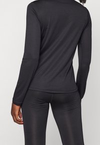 Top negro de manga larga y ajustado, fabricado con un material suave y elástico. Presenta un escote redondo y costuras mínimas para una silueta elegante.