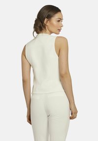Weißes ärmelloses Top mit hohem Kragen, glatter Textur und tailliertem Design. Verfügt über eine klare Silhouette und einen dezenten Rückenschlitz.