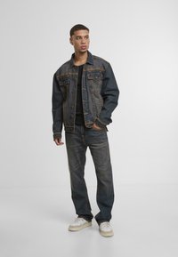 Tume denim jakk koos kontrastsete kollaste õmblustega, ees taskud ja nööbikinnitus. Kombineeritud sobivate tumehallide teksade ja valgete tossudega.