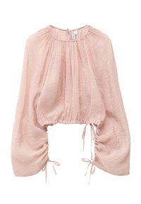 Blouse courte rose clair avec manches longues bouffantes, encolure froncée et cordons réglables aux poignets et à la taille.