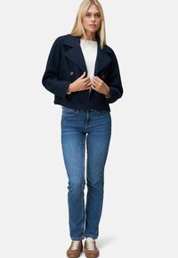 Navy cropped double-breasted jacket with large lapels and gold buttons, paired with light blue jeans and brown sneakers.