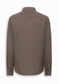Camisa marrón de manga larga con puños abotonados, costura visible en la parte superior de la espalda y cuello clásico, vista desde atrás sobre un fondo blanco.