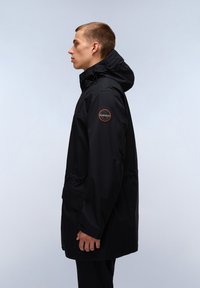 Svart vattentålig jacka med huva, elastiska ärmslut och en logotypapplikation på ärmen. Har en avslappnad passform och sidofickor.