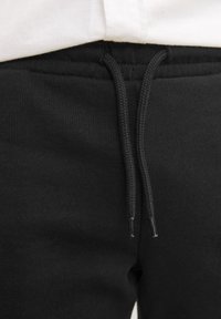 Zwarte katoenen sweatpants met een gemêleerde stof, een elastische tailleband en een verstelbaar trekkoord met plastic tips.