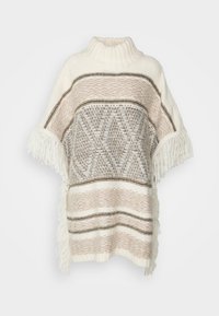 Poncho de malha em creme e bege com um colarinho alto, apresentando padrões geométricos e bordas franjas. Textura suave, forma oversized.