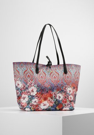 Torba typu tote z czarnymi rączkami, ozdobiona misternymi czerwonymi, niebieskimi i różowymi wzorami paisley i kwiatowymi, umieszczona na białym piedestale.