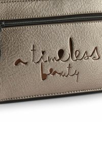Goldene Tasche aus Kunstleder mit geprägtem Text "a timeless beauty", ausgestattet mit Reißverschluss und strukturierter Oberfläche.
