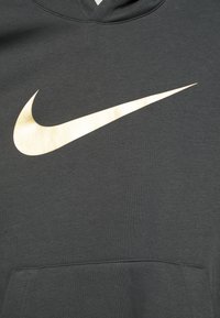Tummanharmaa huppari, joka on valmistettu pehmeästä kankaasta ja jossa on suuri kultainen Nike-logo etupuolella sekä keski-alueen kengurutasku.