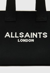 Borsa tote in tessuto nera con branding bianco "ALLSAINTS LONDON", manici robusti e superficie testurizzata.